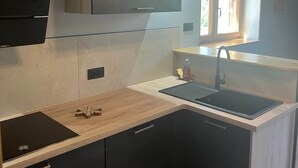 A modern kitchen with a black sink, wooden countertop, and built-in cabinets.