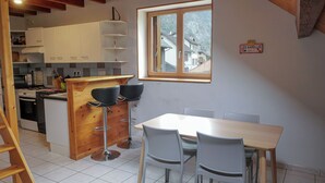 A kitchen with white cabinets, a wooden bar, and a dining area with a table and chairs.