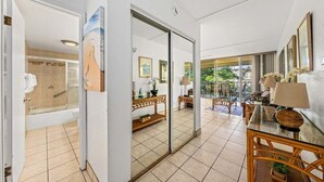 Una habitación de hotel con baño, zona de comedor con vistas y balcón con mobiliario exterior.