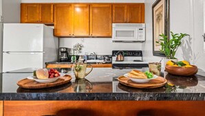 Una cocina moderna con gabinetes de madera, un refrigerador, un microondas, una estufa y una cafetera.