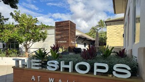 Schild für 'The Shops at Wailea' mit Holzkonstruktion und Grünpflanzen.
