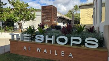 Schild für 'The Shops at Wailea' mit Holzkonstruktion und Grünpflanzen.