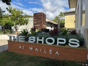 Une enseigne pour « The Shops at Wailea », avec une structure en bois et des éléments de verdure.