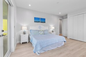 A bedroom with a bed, two bedside tables with lamps, a nightstand, a wardrobe, and a painting on the wall.