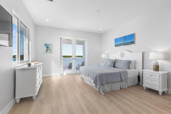 A bedroom with a bed, bedside tables, a dresser, and a view through a glass door.