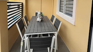A covered patio with a wooden table and chairs, a decorative rabbit statue, and a window with blinds. - American Standard/2Bedroom House (Cagayan de Oro)
