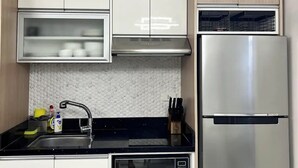 A modern kitchen with white cabinets, a stainless steel refrigerator, a microwave, and a sink with a faucet. - American Standard/2Bedroom House (Cagayan de Oro)