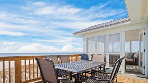 A deck with a table and chairs, overlooking the ocean.