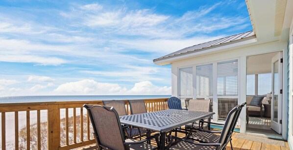 A deck with a table and chairs, overlooking the ocean.