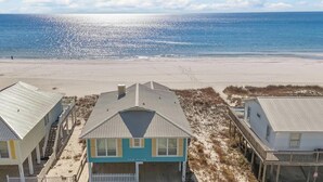 A beachfront property with three houses, a sandy beach, and the ocean in the background.