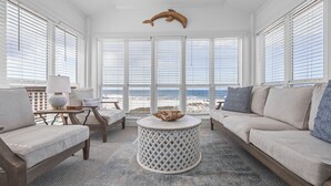 A room with a view of the beach, a round table, and a sofa.