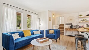 Una sala de estar con un sofá azul, una barra para café y una escalera que sube a otro nivel.