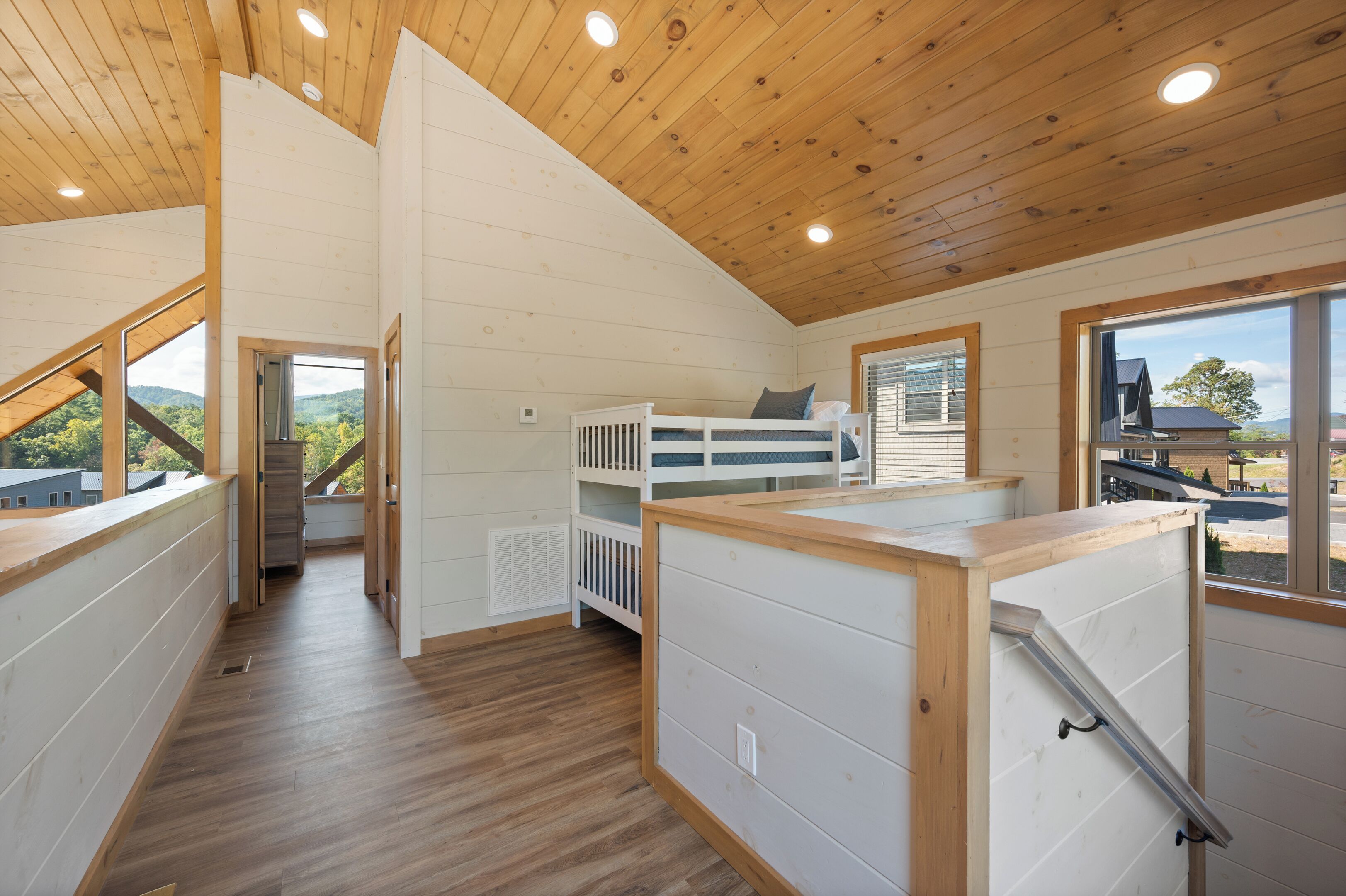 Une pièce spacieuse avec un lit superposé, un plafond en bois et de grandes fenêtres donnant sur l’extérieur.