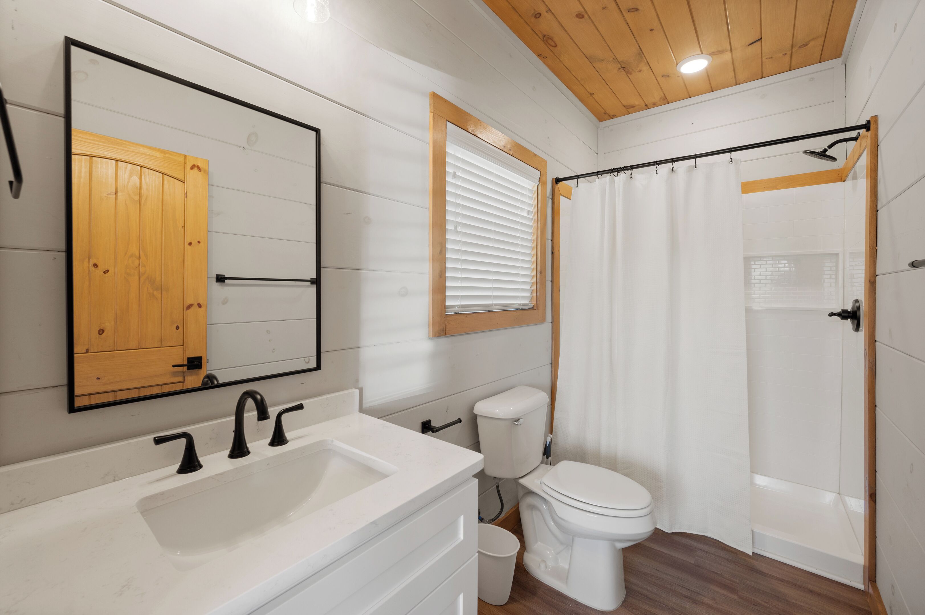 A bathroom with a white sink, a toilet, and a shower with a wooden door.