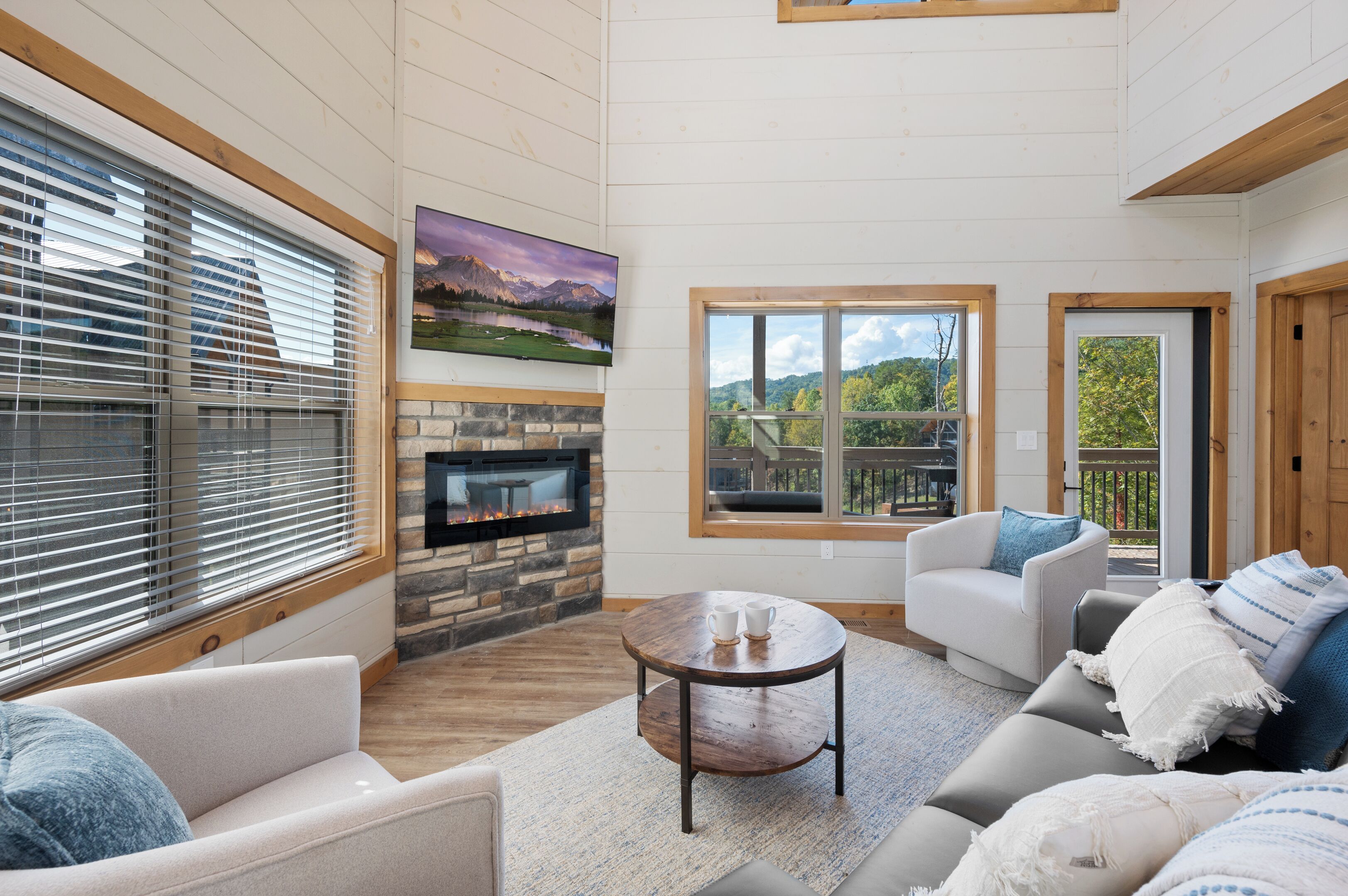 A living room with a fireplace, a large window with a view, and a cozy seating area.