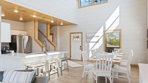 A modern kitchen with a central island, white cabinetry, and a stainless steel refrigerator. - New cabin! Great Location! 5 Min to Parkway! Private pool, hot tub, & game room! (Pigeon Forge)
