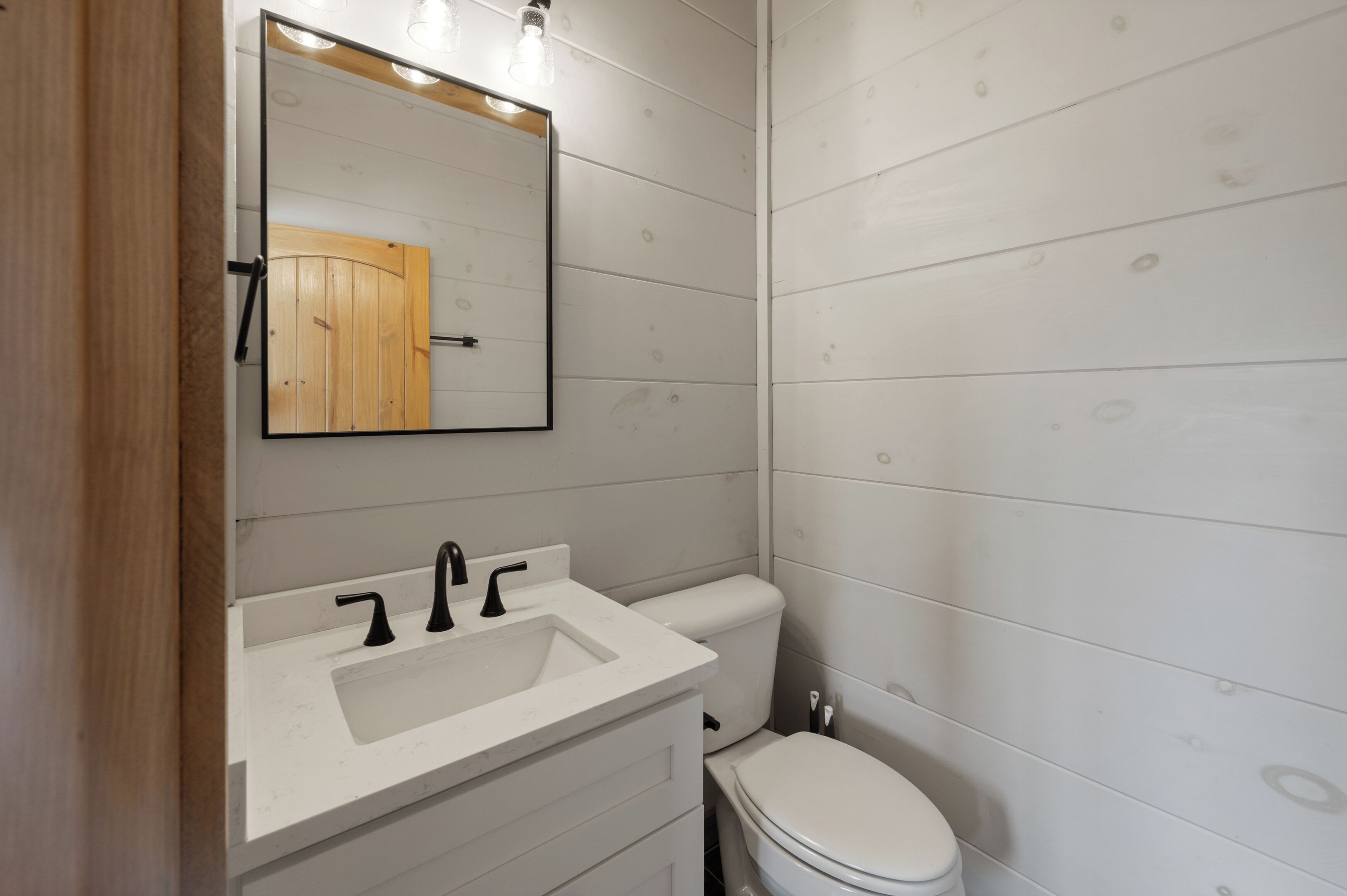 Een badkamer met een witte wasbak, een zwarte kraan en een wit toilet.