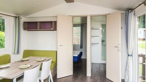 Une chambre compacte et moderne, dotée d’un coin repas, d’un petit lit et d’une douche.