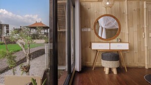 Una habitación con un tocador de madera, un espejo redondo y un taburete de mimbre.