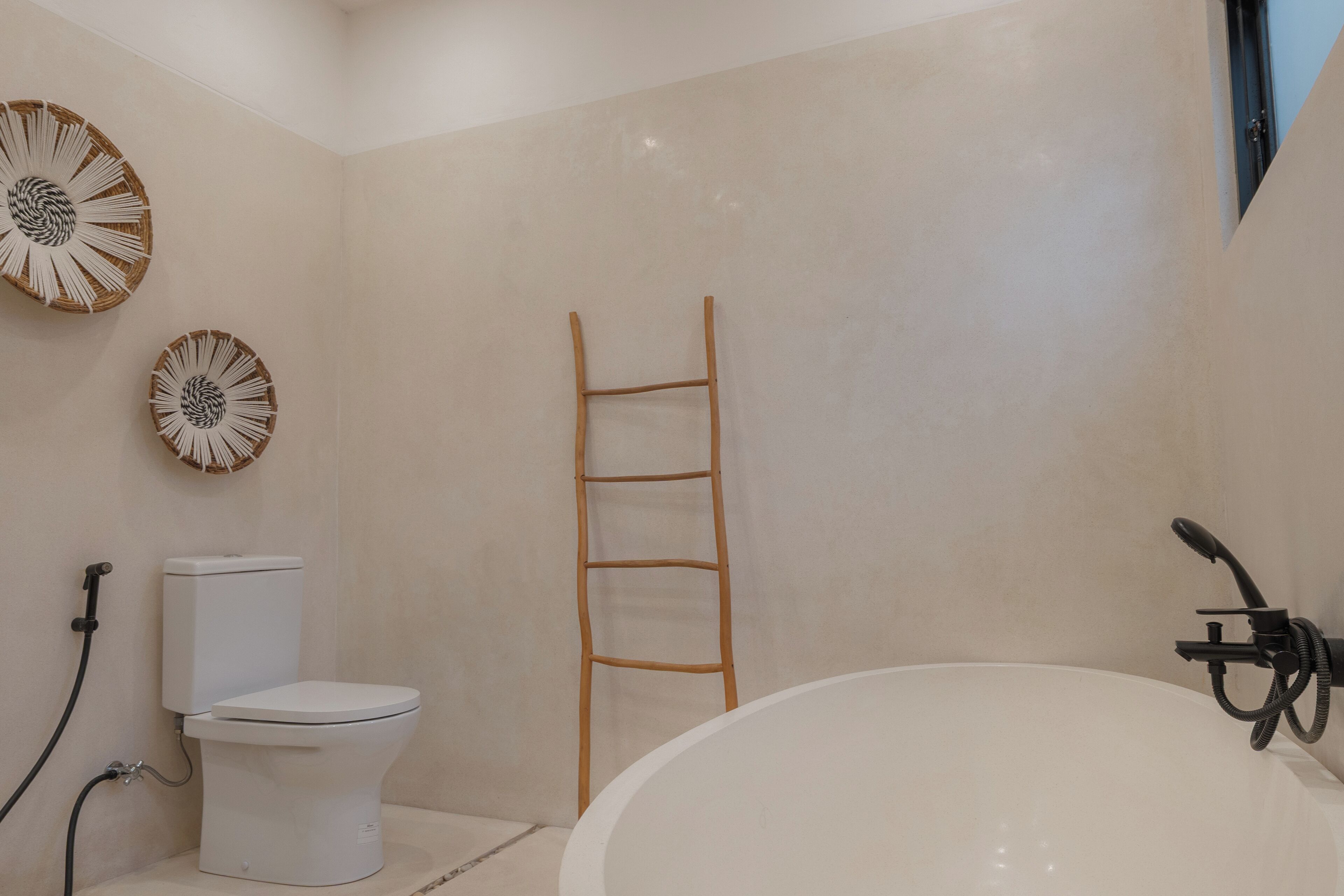 A bathroom with a toilet, a bathtub, and a wooden ladder.