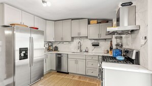 Eine moderne Küche mit Edelstahlgeräten, weißen Schränken und einer Marmor-Spritzschutzwand.