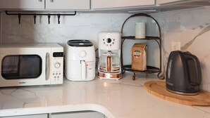 Eine Küche mit Mikrowelle, Kaffeemaschine und Wasserkocher auf der Arbeitsfläche.