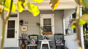 Eine Veranda mit zwei Schaukelstühlen, einem kleinen Tisch und einem Blumentopf.