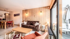 Uma sala de estar moderna com parede de madeira, um sofá marrom, uma mesa de centro de madeira e uma poltrona vermelha.