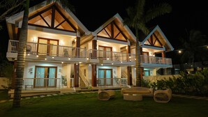 A two-story building with balconies, string lights, and outdoor seating. - Caza Guesthouse Iyang (Concepcion)