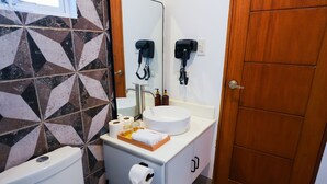 A bathroom with a white sink, a mirror, a toilet, and a cabinet with toiletries. - Caza Guesthouse Iyang (Concepcion)