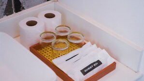 A white box containing a guest kit with toiletries, including two rolls of toilet paper, four small glass bottles, and a white bag labeled "GUEST KIT". - Caza Guesthouse Iyang (Concepcion)