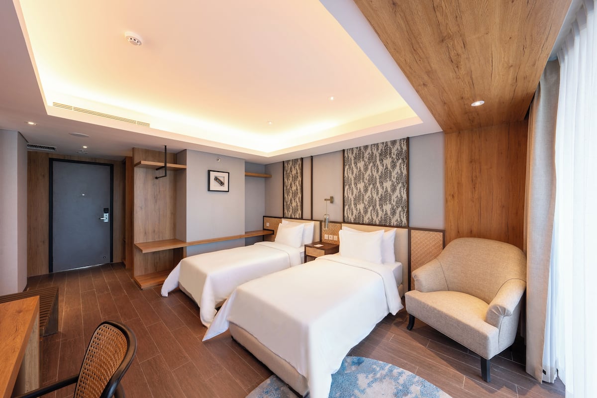 A hotel room with two beds, a sofa, a desk, and a chair.