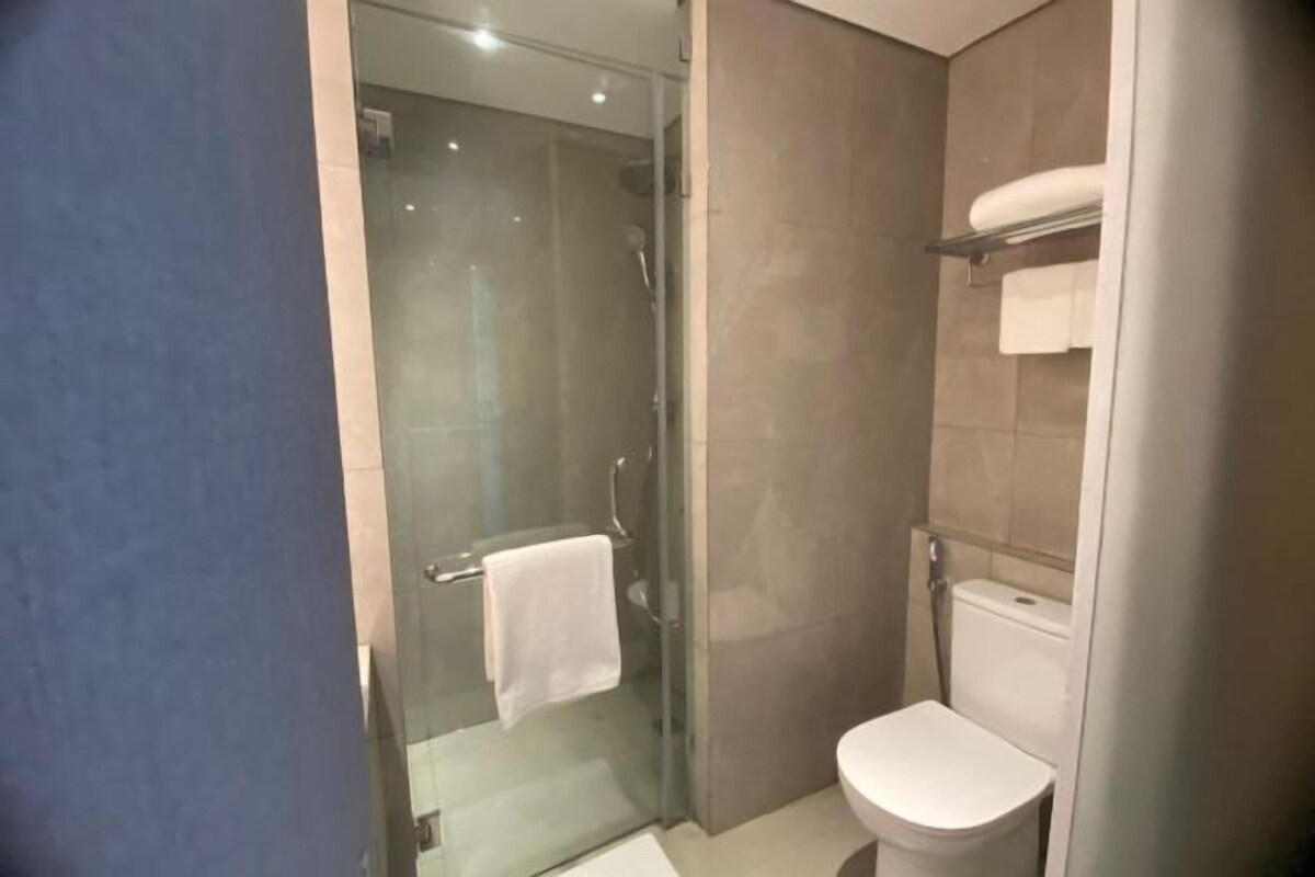 A modern bathroom with a glass-enclosed shower, a white toilet, and a towel rack.