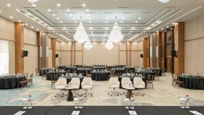 Un amplio salón de conferencias con varias mesas y sillas, candelabros y suelo alfombrado.