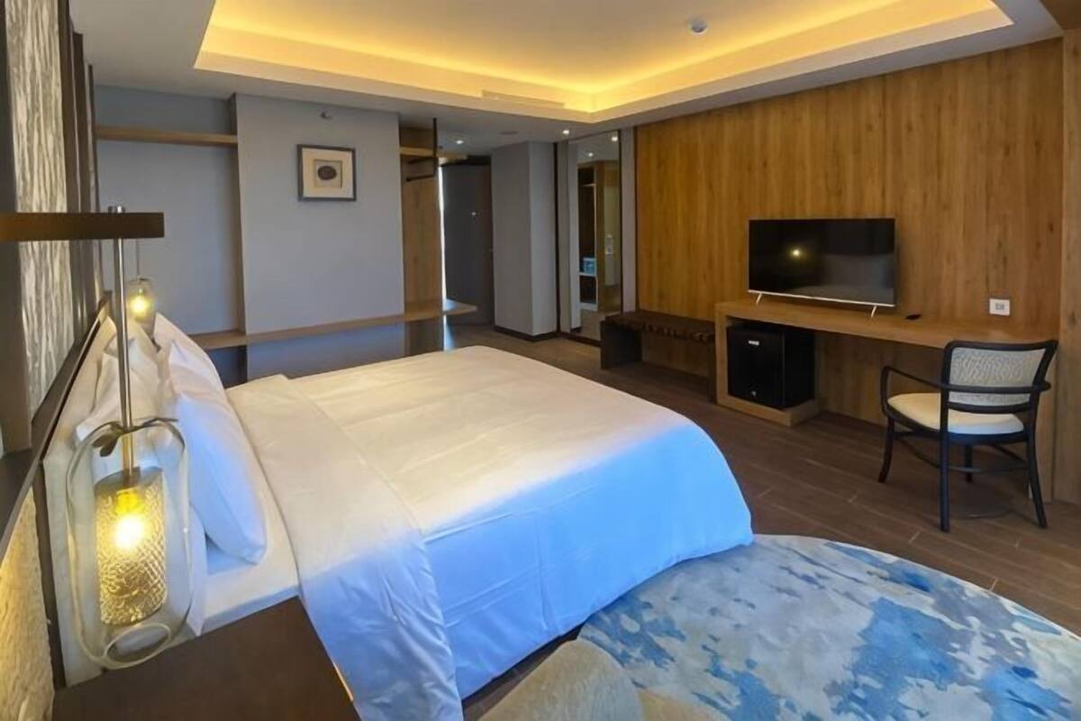 A hotel room with a bed, a TV, a desk, and a chair.