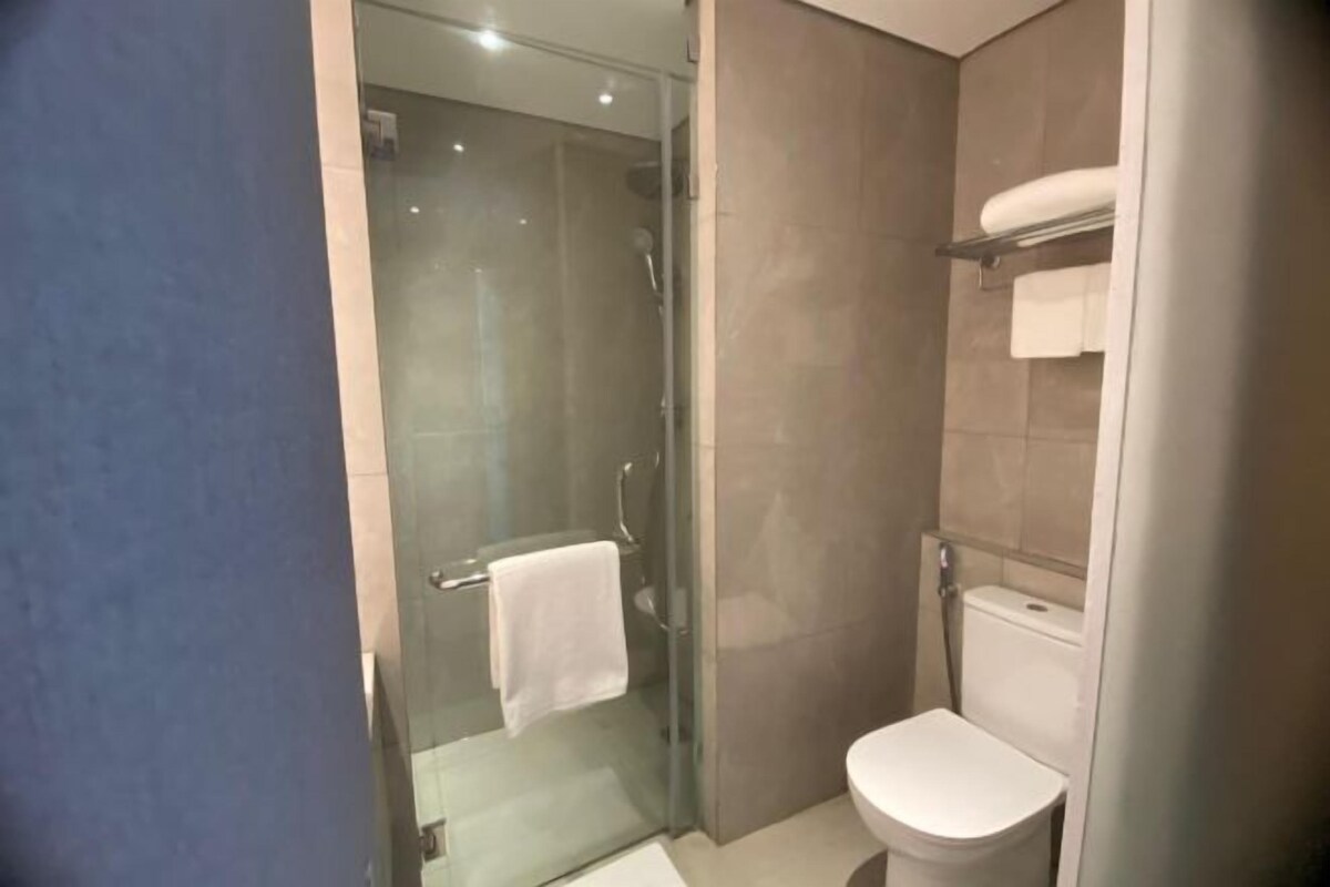 A modern bathroom with a glass shower enclosure, a white toilet, and a towel rack.