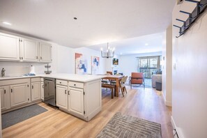 A modern kitchen with white cabinetry, a central island, and a dining area with a table and chairs.