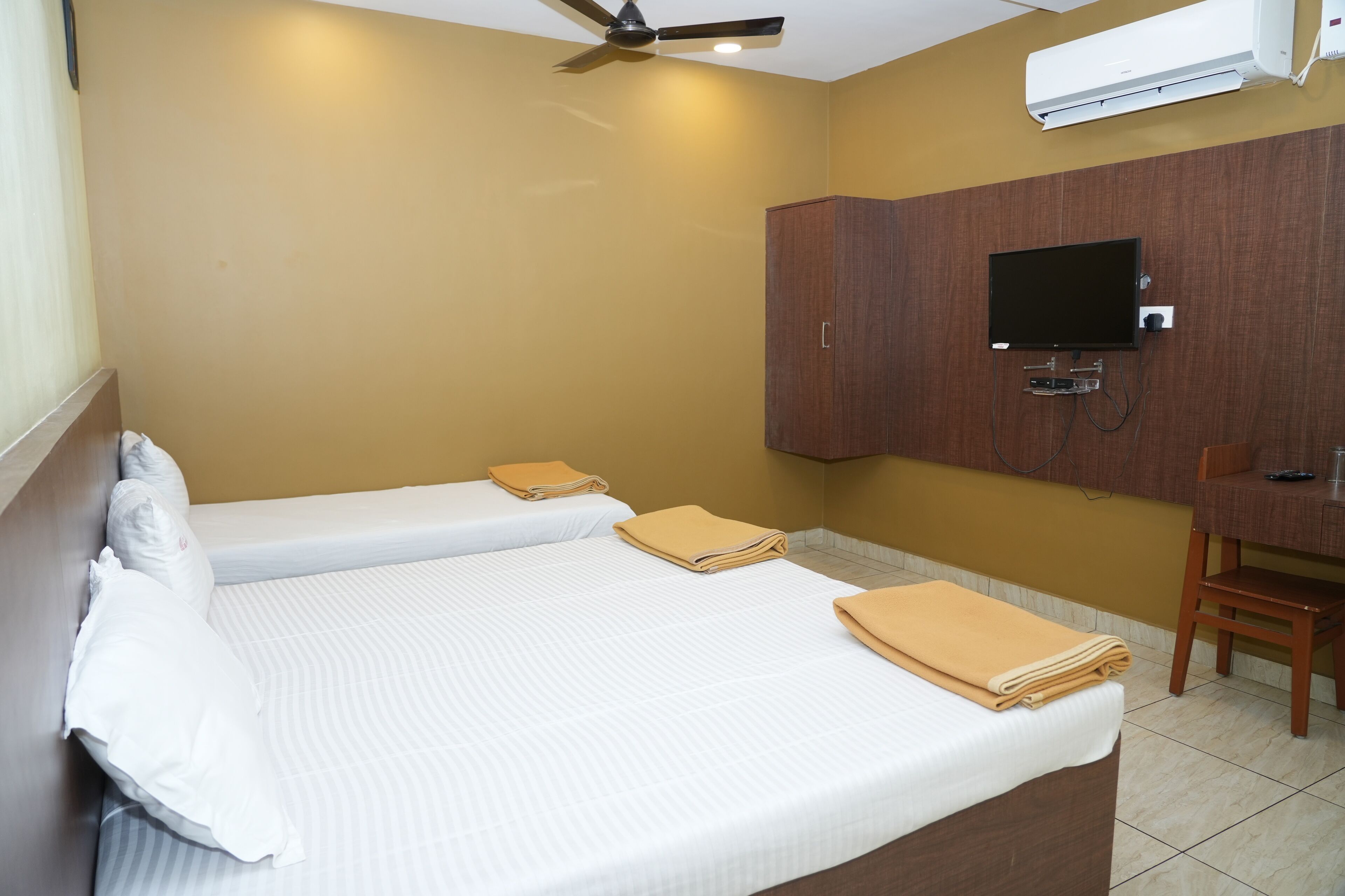 A hotel room with two beds, a TV, and a wooden cabinet.