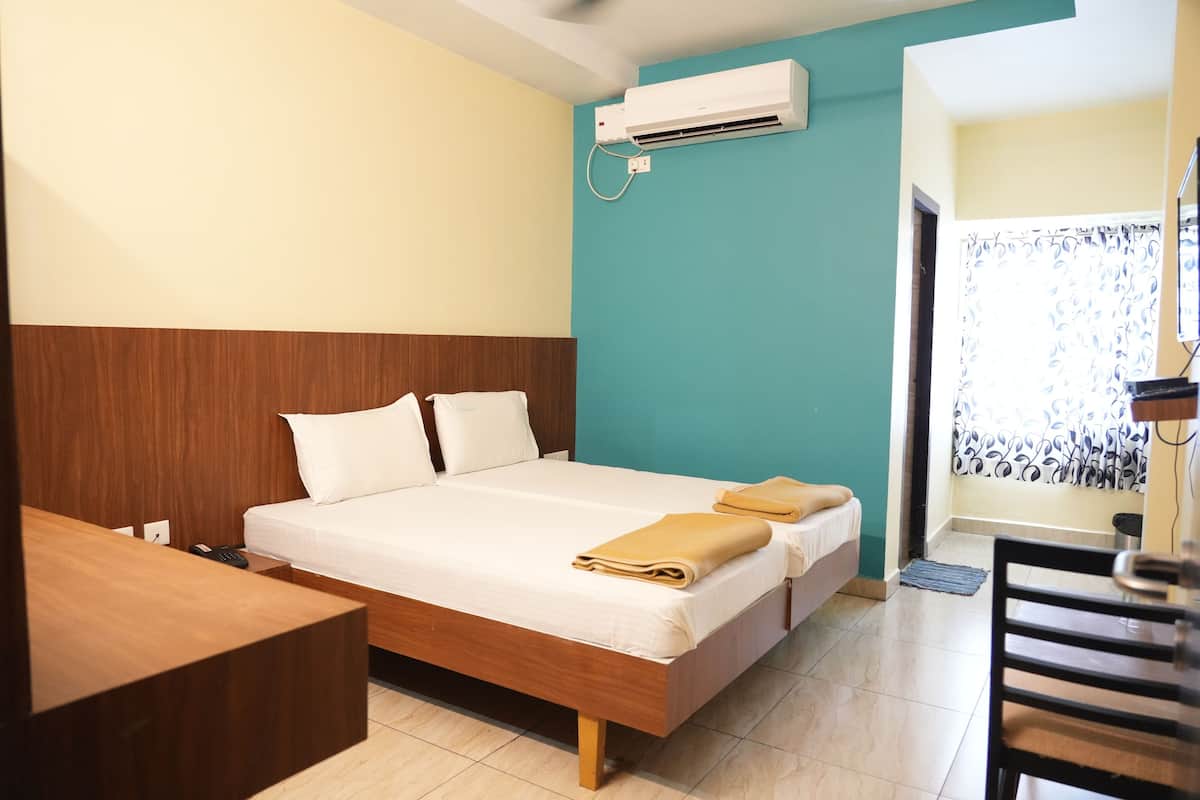 Una habitación de hotel con una cama de madera, un escritorio y un aire acondicionado en la pared.