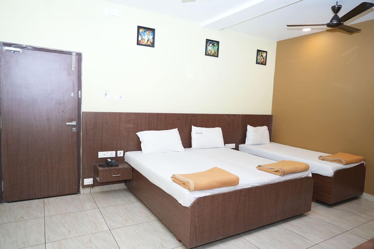 Habitación de hotel con dos camas individuales, un cabecero de madera, una mesita de noche pequeña con un teléfono e un ventilador de techo.