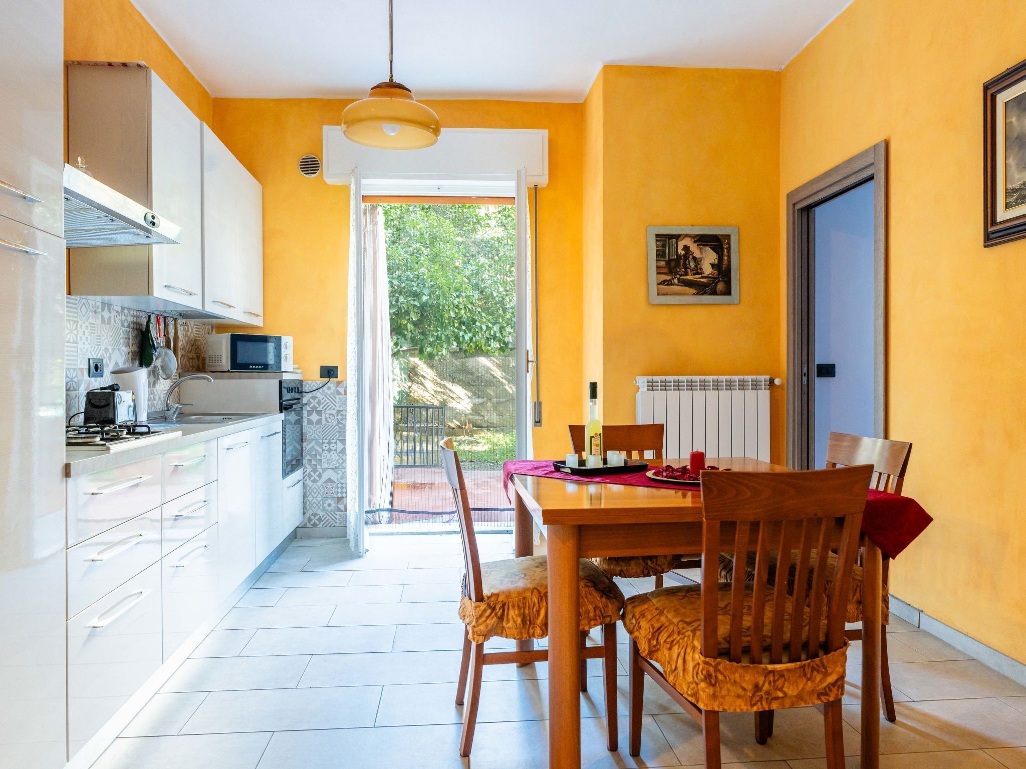 A modern kitchen with white cabinets, a microwave, and a dining area with a wooden table and chairs.