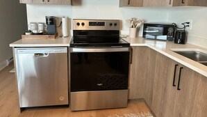 Una cocina funcional con lavavajillas, estufa, microondas y armarios de madera.