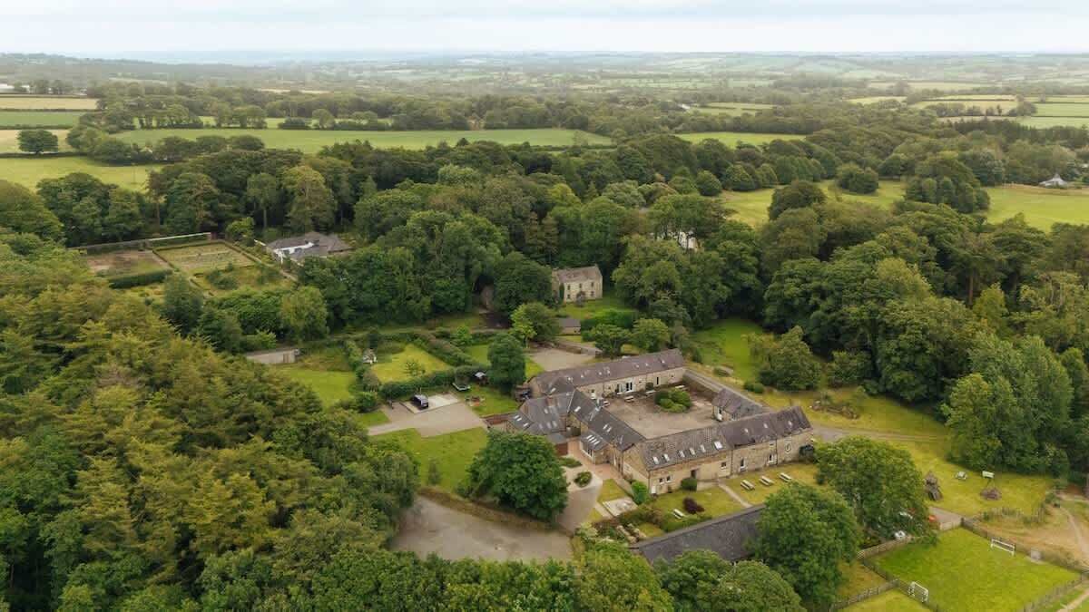 An aerial view of a historic estate with a large central building surrounded by extensive gardens and fields.