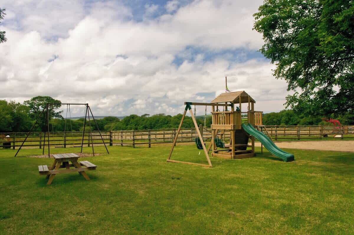 A playground with swings, a slide, and a picnic table.