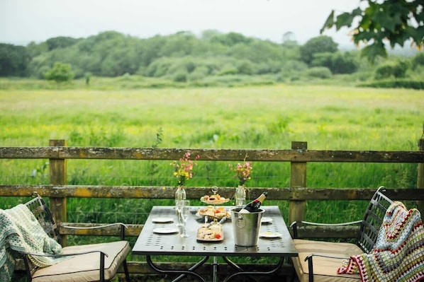 Un espace de restauration en plein air avec une table, des chaises et une vue sur un champ verdoyant.