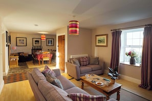 A living room with a sofa, coffee table, and dining area with a table and chairs.