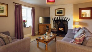 A living room with a fireplace, sofa, television, and a wooden coffee table.