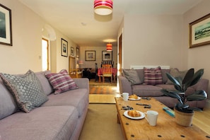 A living room with two sofas, a coffee table, and a dining area with a table and chairs.