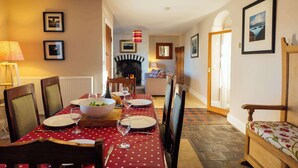 A dining area with a red tablecloth, chairs, a fireplace, and framed pictures on the walls.