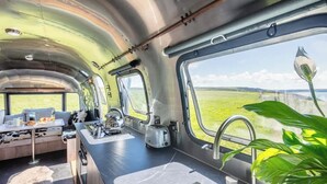 A modern kitchen with a large window, a sink, and a kettle. - Airstream with Stunning Coastal Views. (Nolton Haven)